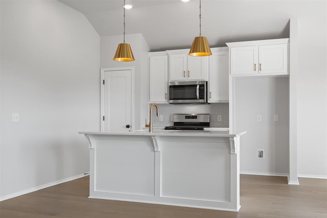 kitchen featuring stainless steel appliances, pendant lighting, decorative backsplash, a center island with sink, and white cabinets