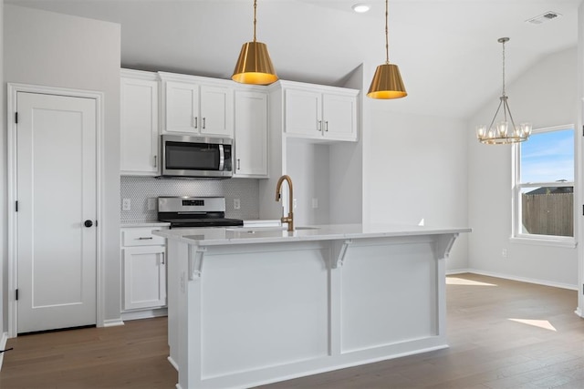 kitchen with a kitchen island with sink, hanging light fixtures, lofted ceiling, and appliances with stainless steel finishes