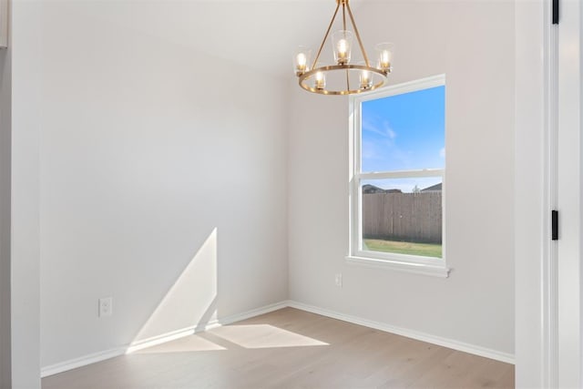 empty room featuring light hardwood / wood-style flooring and a chandelier