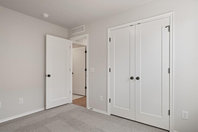 unfurnished bedroom featuring light carpet and a closet