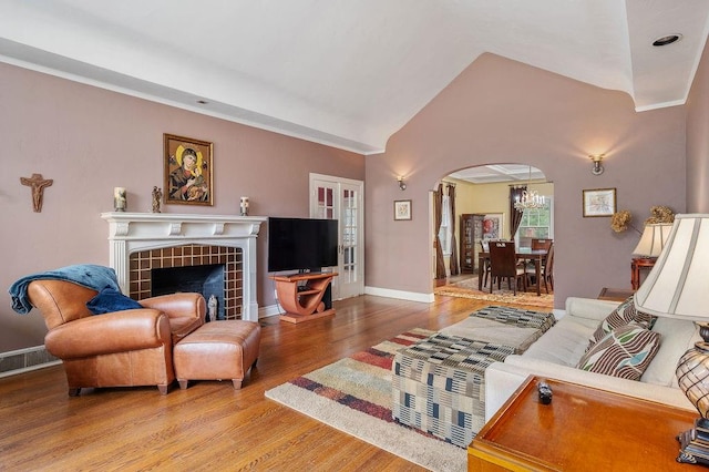 living room featuring a tiled fireplace, hardwood / wood-style floors, and lofted ceiling