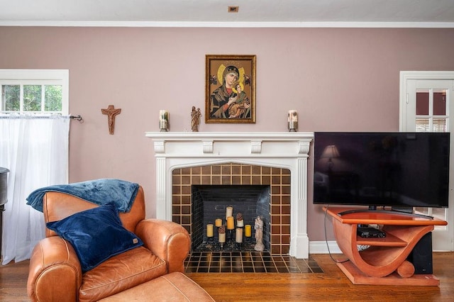 living room featuring dark hardwood / wood-style flooring, crown molding, and a tile fireplace