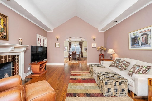 living room featuring lofted ceiling, an inviting chandelier, wood-type flooring, and a tiled fireplace