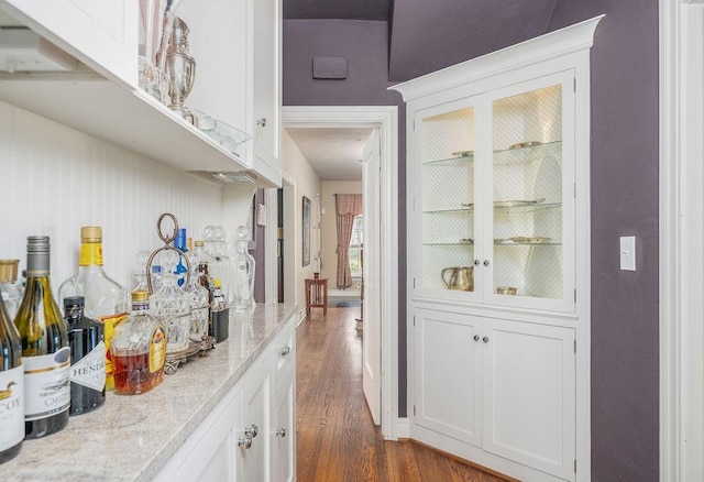 bar with white cabinetry, light stone countertops, and dark hardwood / wood-style floors