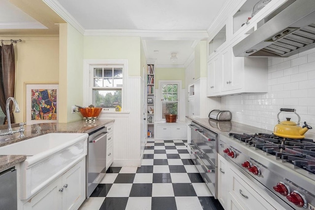 kitchen featuring backsplash, white cabinets, wall chimney range hood, and appliances with stainless steel finishes