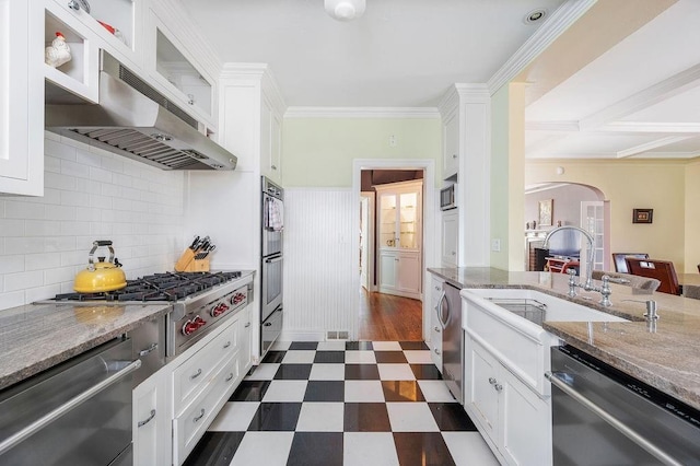 kitchen with white cabinets, appliances with stainless steel finishes, ventilation hood, and light stone counters