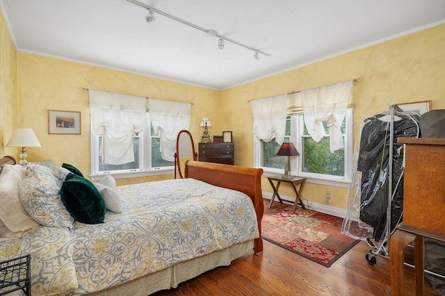 bedroom featuring hardwood / wood-style floors, ornamental molding, and rail lighting