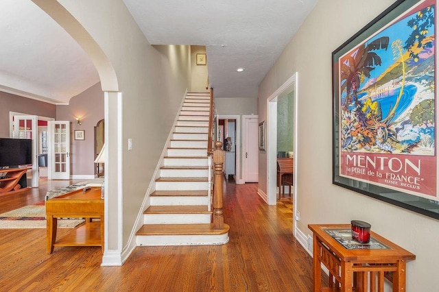 staircase with wood-type flooring and french doors