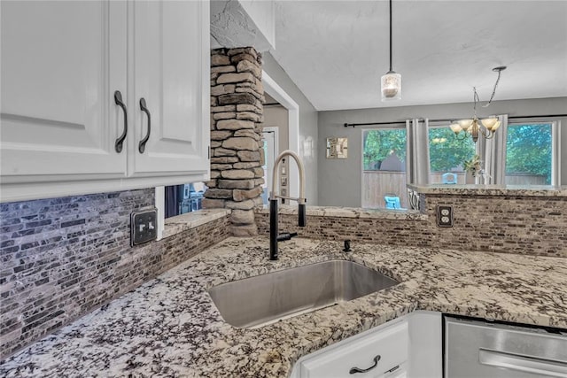 kitchen featuring backsplash, sink, pendant lighting, a notable chandelier, and white cabinetry