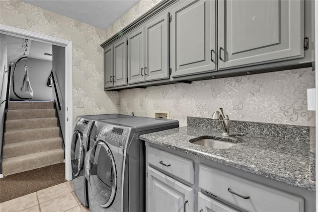 washroom featuring washer and dryer, sink, light tile patterned floors, and cabinets