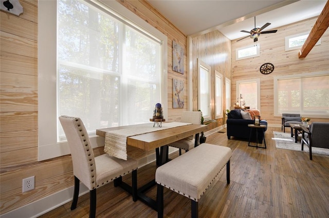 dining area featuring ceiling fan and wooden walls