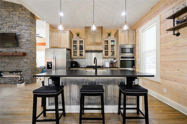 kitchen featuring a breakfast bar area, dark hardwood / wood-style flooring, light brown cabinets, and appliances with stainless steel finishes