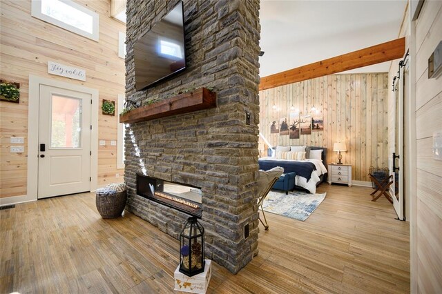 interior space featuring beamed ceiling, light hardwood / wood-style flooring, a fireplace, and wood walls