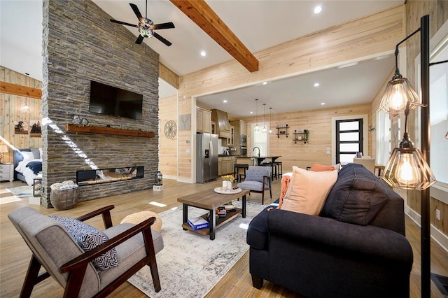 living room featuring a fireplace, light hardwood / wood-style flooring, ceiling fan, and wood walls