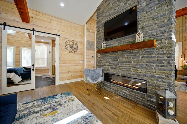 living room with hardwood / wood-style flooring, a stone fireplace, and wooden walls