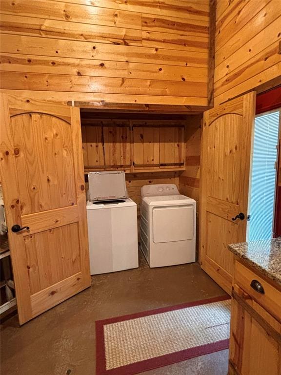 washroom featuring wood walls, cabinets, and independent washer and dryer