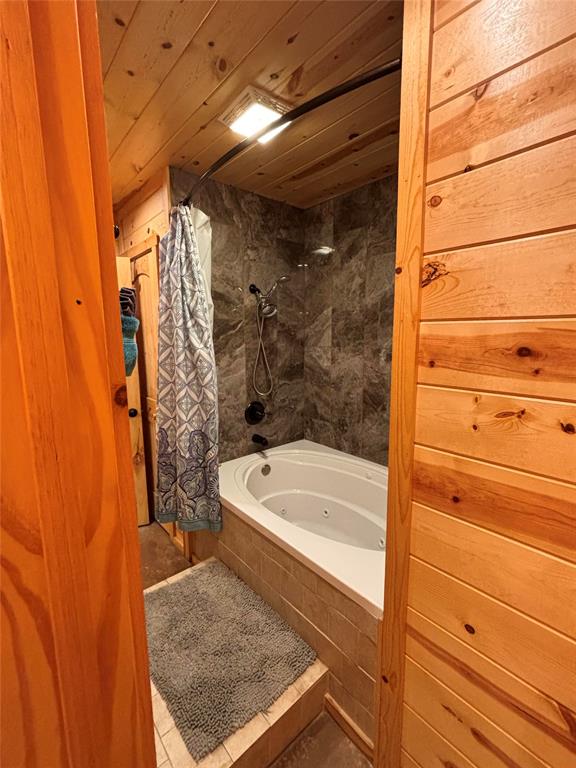 bathroom with shower / bath combo with shower curtain, wooden ceiling, and tile patterned flooring