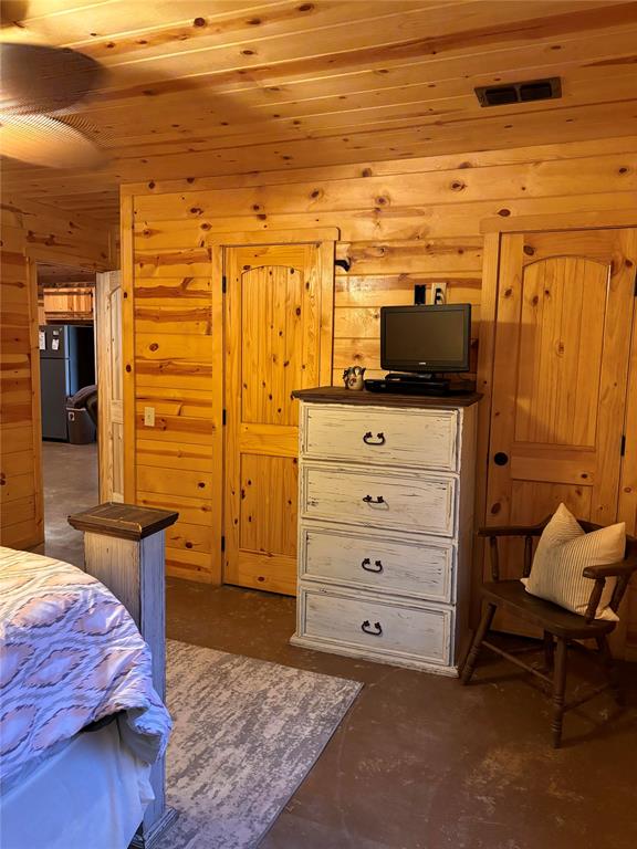 bedroom with black fridge, wood ceiling, and wood walls