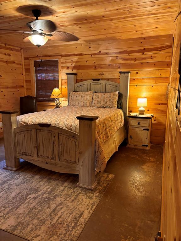 bedroom with ceiling fan, wooden walls, and wooden ceiling