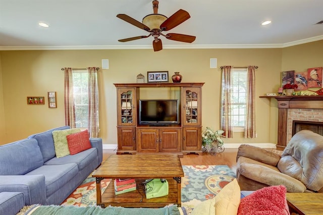 living room featuring a brick fireplace, ceiling fan, wood-type flooring, and ornamental molding