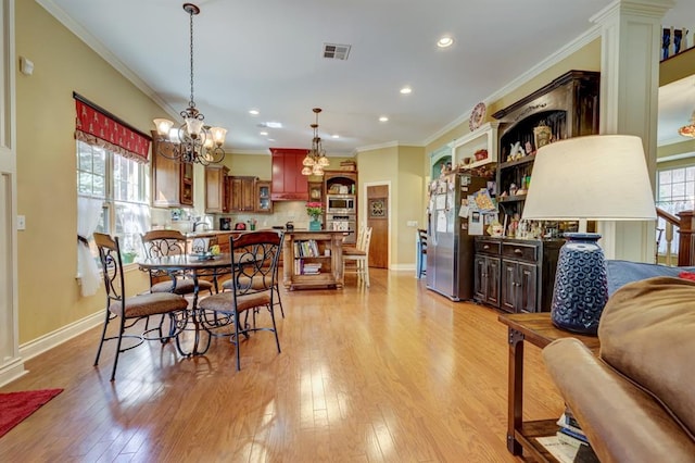 dining room with crown molding, plenty of natural light, and light hardwood / wood-style floors