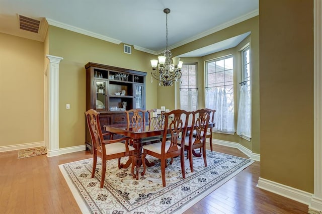 dining area with wood-type flooring, ornamental molding, and ornate columns