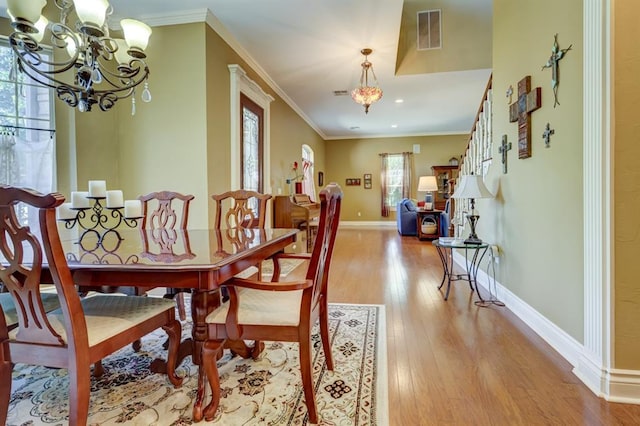 dining area with a chandelier, light wood-type flooring, plenty of natural light, and crown molding