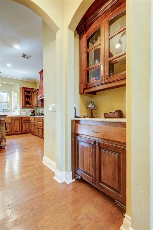 bar featuring light stone countertops, light wood-type flooring, and ornamental molding