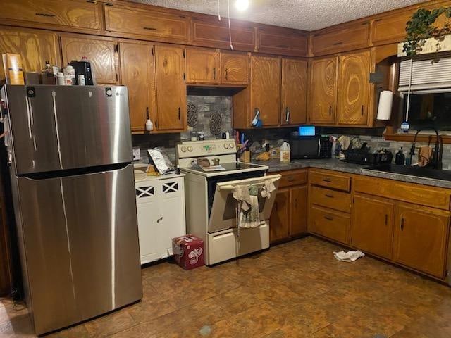 kitchen with sink, white range with electric stovetop, stainless steel fridge, a textured ceiling, and decorative backsplash