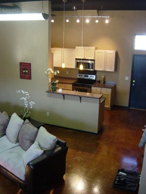 kitchen with white cabinets, stainless steel appliances, a kitchen bar, and a peninsula