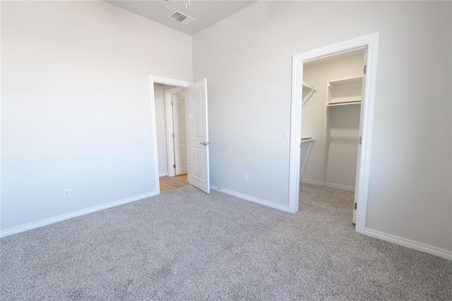 unfurnished bedroom with a spacious closet, light colored carpet, and a closet