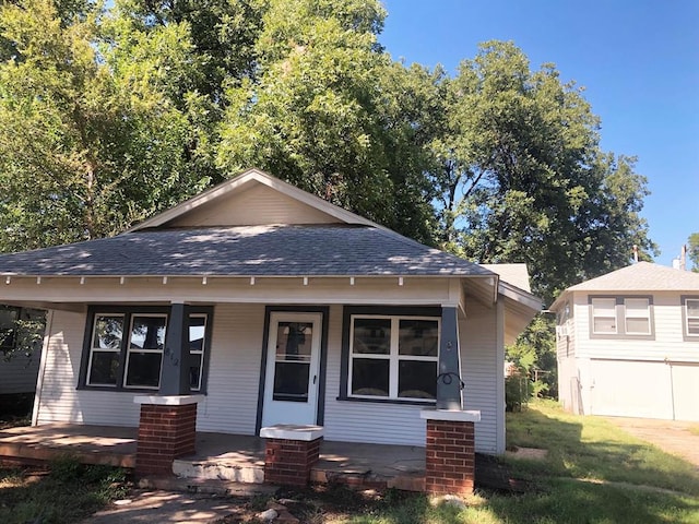 bungalow featuring covered porch and a front yard