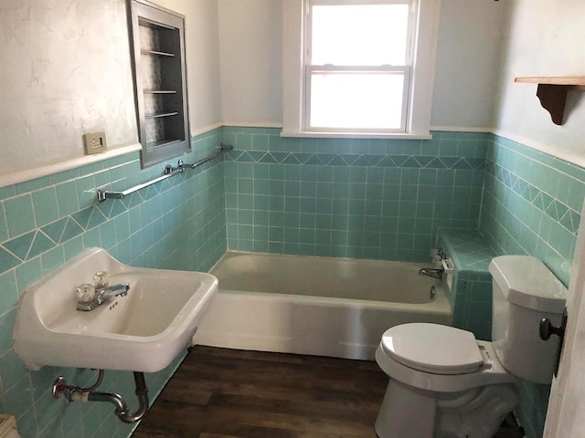 bathroom featuring a bathtub, sink, hardwood / wood-style flooring, tile walls, and toilet