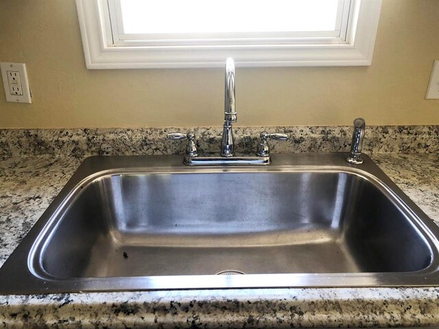 details with white cabinetry, sink, and stone counters