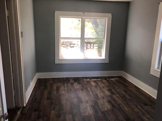 empty room featuring dark wood-type flooring and a healthy amount of sunlight