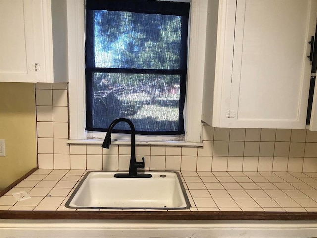 kitchen featuring tasteful backsplash, white cabinetry, tile counters, and sink