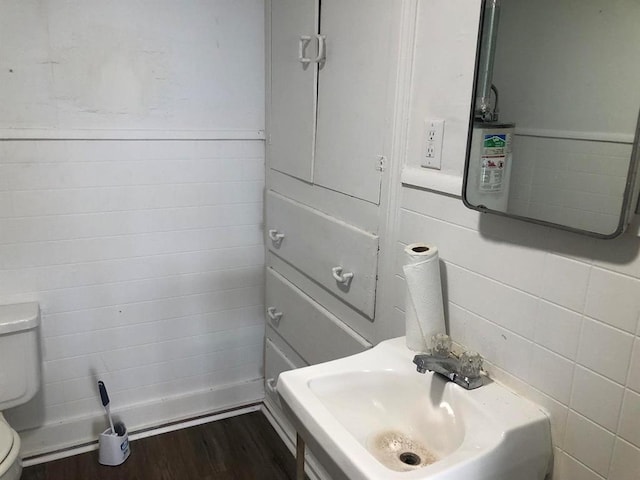 bathroom with toilet, wood-type flooring, sink, and tile walls