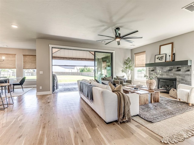 living room featuring light hardwood / wood-style flooring, ceiling fan, and a healthy amount of sunlight