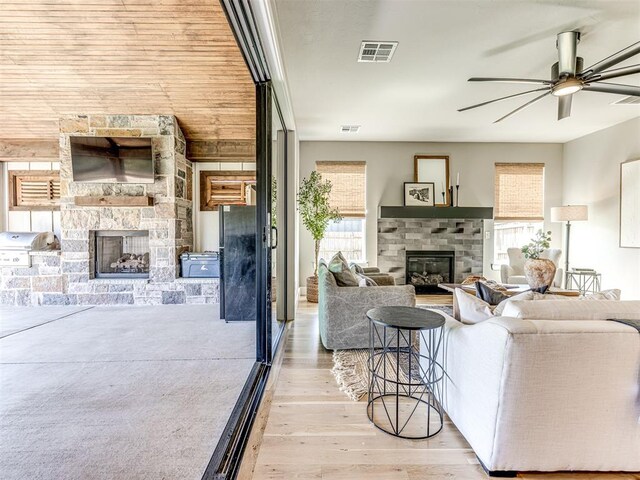 living room featuring ceiling fan, a fireplace, and light hardwood / wood-style flooring