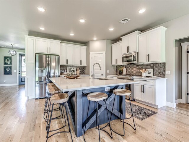 kitchen with white cabinets, stainless steel appliances, light hardwood / wood-style flooring, and sink