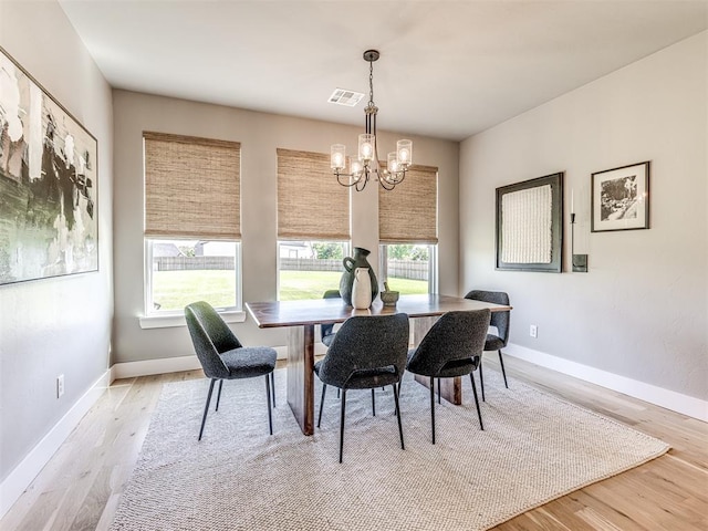 dining room featuring a chandelier, a healthy amount of sunlight, and light wood-type flooring