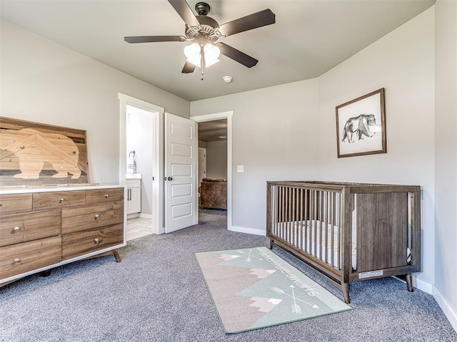 unfurnished bedroom featuring light carpet, ensuite bath, ceiling fan, and a crib