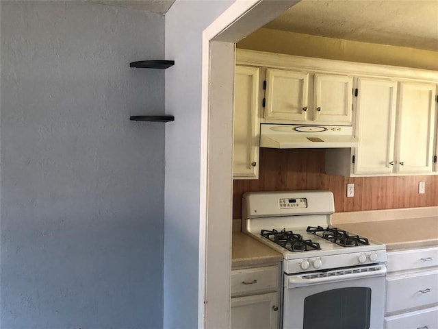 kitchen with white gas stove and white cabinetry