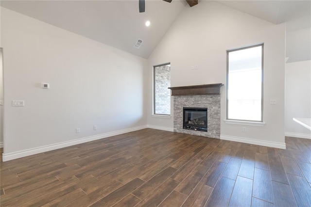 unfurnished living room with a healthy amount of sunlight, a fireplace, high vaulted ceiling, and dark wood-style flooring