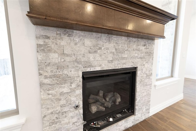 details featuring a glass covered fireplace, wood finished floors, and baseboards