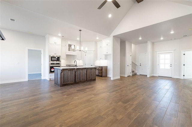 kitchen with open floor plan, appliances with stainless steel finishes, dark wood finished floors, and white cabinetry