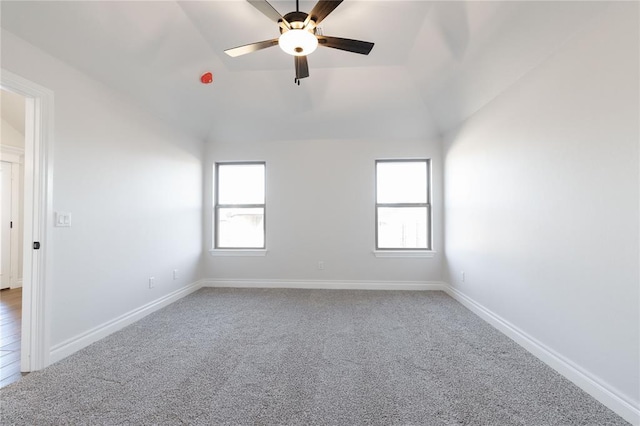 empty room with lofted ceiling, a wealth of natural light, and baseboards