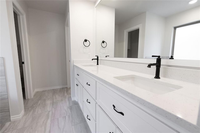 bathroom with double vanity, baseboards, and a sink