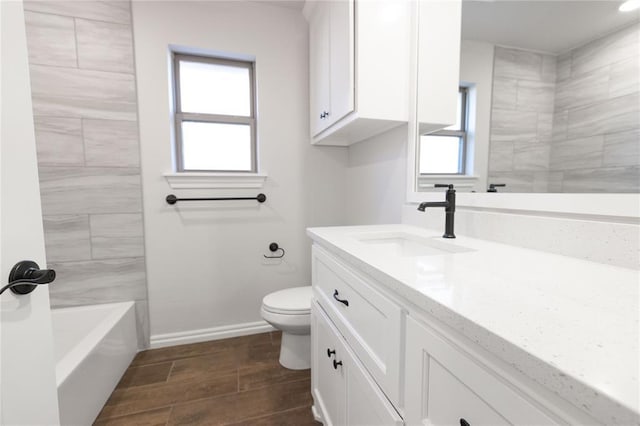 bathroom featuring toilet, baseboards, wood finish floors, and vanity