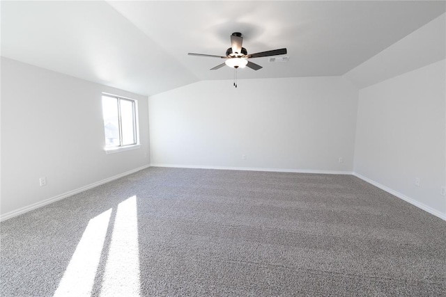 carpeted spare room with lofted ceiling, baseboards, visible vents, and ceiling fan